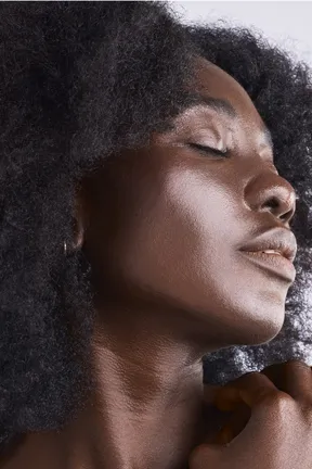 Mannequin à la peau brune foncée, aux cheveux noirs et aux yeux très foncés, illustrant le phototype V : une peau très résistante au soleil.