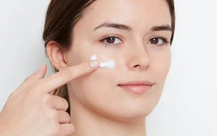 Mannequin brune aux yeux marron utilisant une crème de couleur blanche, plus précisément la crème de soin clarté du teint.