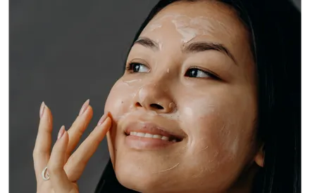 Mannequin étalant sur son visage notre gommage délicat aux AHA, un gommage sous forme de masque-crème.