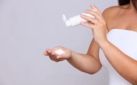 Gros plan sur les mains du mannequin : une main tient le flacon, l'autre reçoit la poudre de gommage Earl Grey. Ce soin s'applique sur le corps préalablement humidifié.