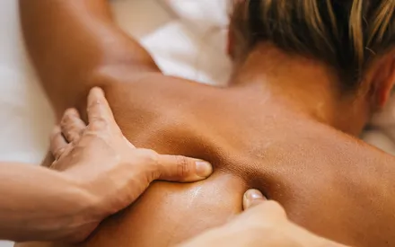 Dos d'une femme qui se fait masser en institut avec le baume de massage aux huiles essentielles pour éliminer les tensions du quotidien