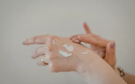 Deux mains en train d’étaler la crème mains bergamote pour des mains de velours.