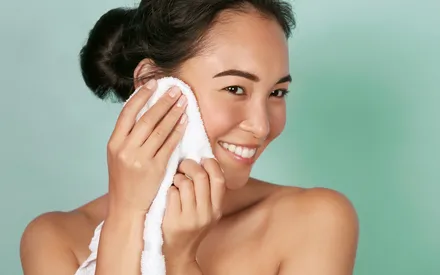 Un mannequin asiatique à la peau zéro défaut essuie son visage après le rinçage de la Mousse Nettoyante purifiante Clear Expert.