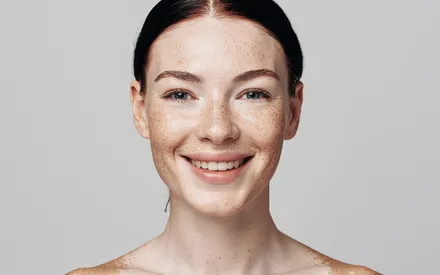 Portrait d'une femme rousse aux taches de rousseur, affichant une peau nette et un teint éclatant après l'utilisation du gommage Enzym'Active Gel.