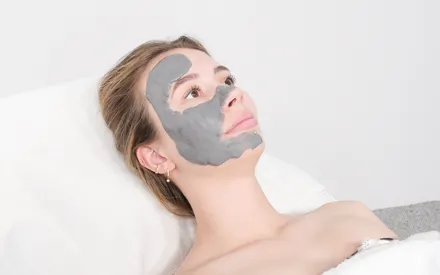 Un mannequin arborant un masque en poudre qui se réhydrate en une texture crème onctueuse à l'aide d'un shaker. De couleur gris charbon, ce soin au charbon actif, au cœur de sa formule, permet de lutter contre la pollution et protège la peau.