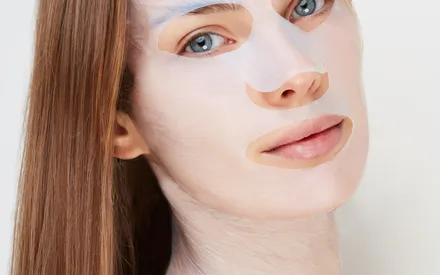 Portrait d'un mannequin portant un masque de soin en biocellulose, intensément imprégné d'un sérum anti-âge. La texture seconde peau du masque épouse parfaitement les contours du visage et se prolonge jusqu'au cou pour une efficacité optimale.