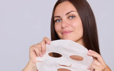Mannequin de face tenant un masque en tissu Softcell hydra-masque dans ses mains, un masque prêt à l'emploi
