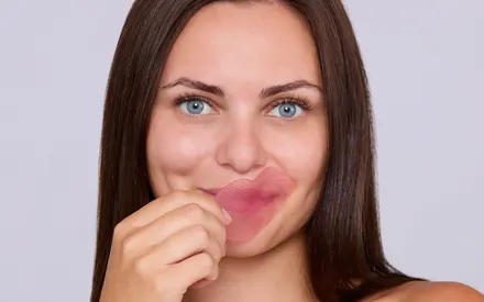 Mannequin qui retire un patche hydrogel pour les lèvres de couleurs rose et de texture hydrogel.