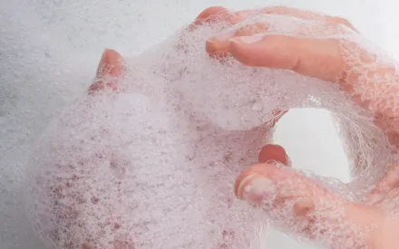 Photo d'une main avec de la mousse pour illustrer la réhydratation de ce gel douche en poudre..