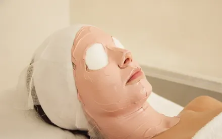 Mannequin avec un masque thermique posé sur le visage. Ses yeux sont recouverts de cotons. Il s'agit d'un masque en poudre réhydraté, de couleur rosée.