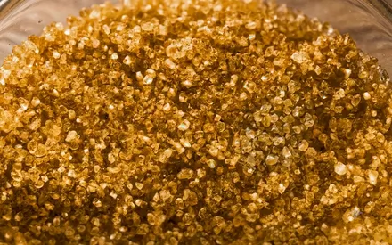 L'image est une photographie macro en très gros plan montrant une accumulation dense de grains de sel de bain teintés d'une couleur dorée.