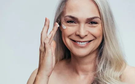 Femme avec une peau mature qui s'applique la crème confort anti-âge sur sa peau 